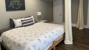 A bedroom with a bed, a nightstand, a wall-mounted lamp, a door, and a curtain. - Das Gästehaus • 50 Min to KC Stadium • World Cup 2026 (Concordia)