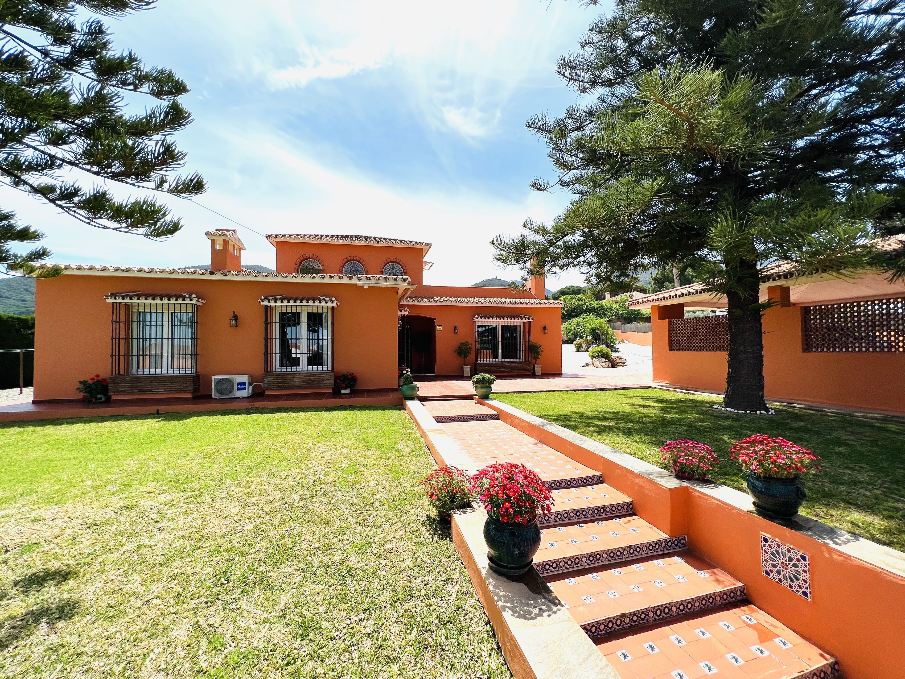 A two-story house with a tiled roof, a small front porch, and a well-maintained lawn.