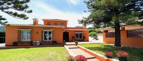 A two-story house with a tiled roof, a small front porch, and a well-maintained lawn.