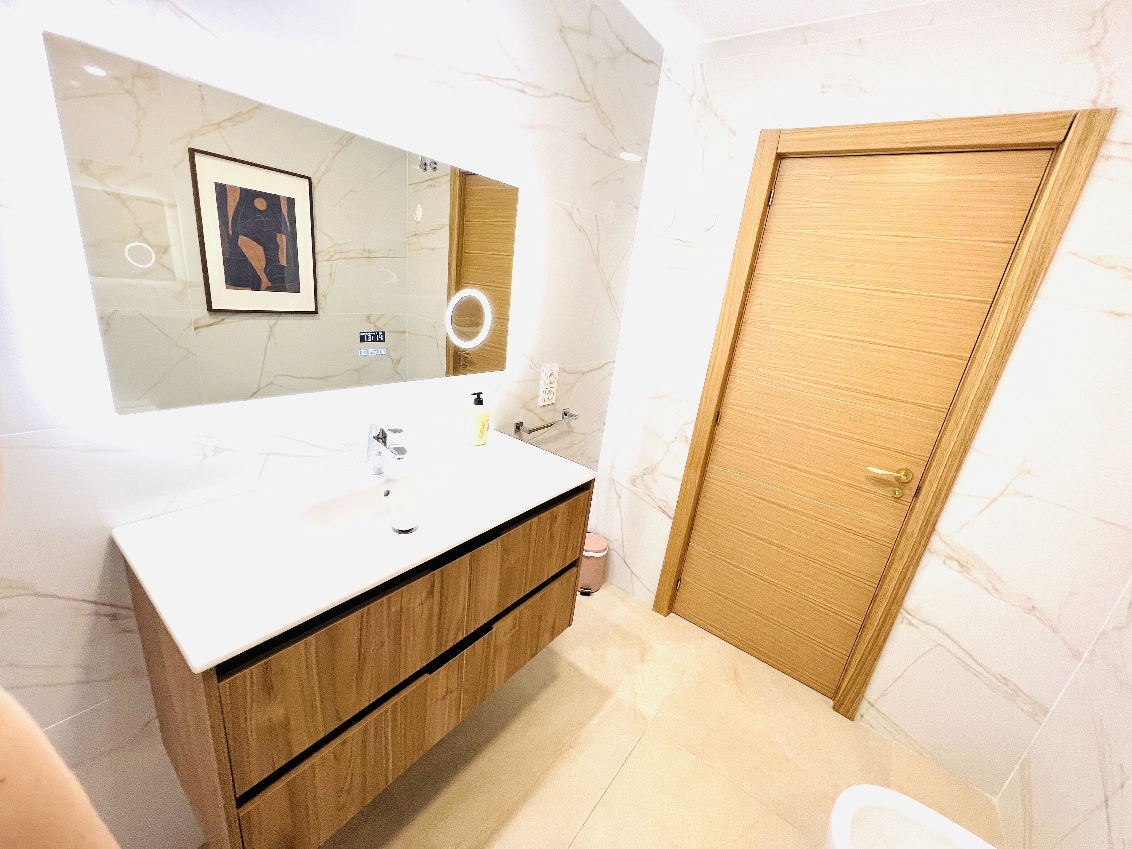Une salle de bain avec un mur en marbre, un meuble-lavabo en bois, un lavabo avec un miroir et une porte en bois.