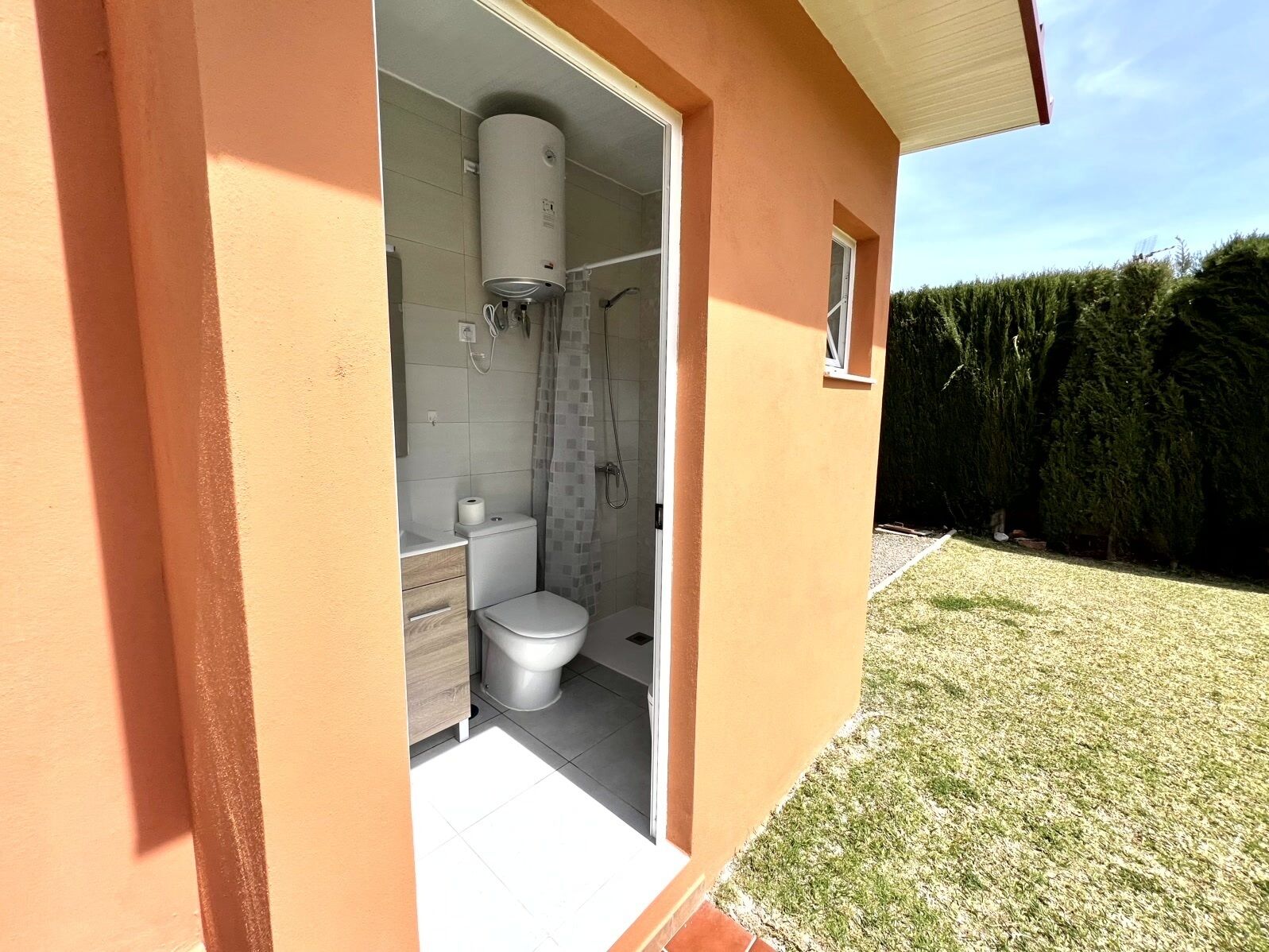 Une salle de bain équipée de toilettes, d’une douche et d’un chauffe-eau.
