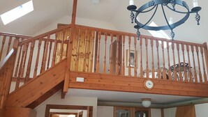 A wooden staircase with a chandelier, a clock, and a statue on the landing. - Cosy Cottage with Log burner very tranquil in gorgeous rural setting (Huntly)