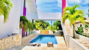 A modern pool area with a clear blue pool, surrounded by white walls and a pink accent wall. - Artistic Mayan Accommodations - AMA 2C (Boulevard Turístico Bording)
