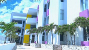 A modern building with a white facade and purple accents, featuring a central yellow pillar and multiple balconies. - Artistic Mayan Accommodations - AMA 2C (Boulevard Turístico Bording)