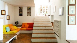 A staircase leading to a second floor, a bright orange sofa with cushions, and a globe on a small table.