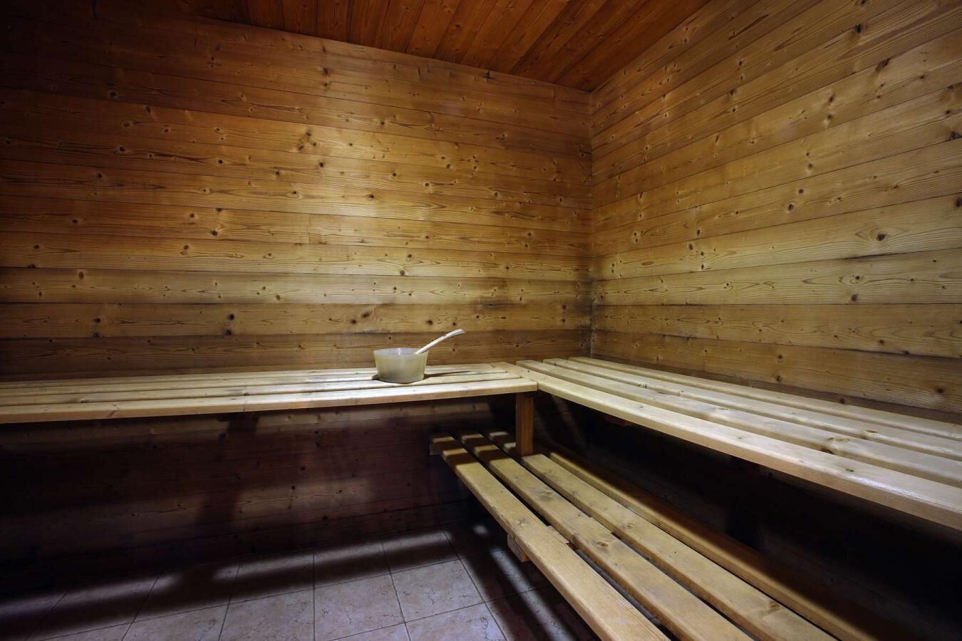 A sauna with wooden benches and a single empty bench.