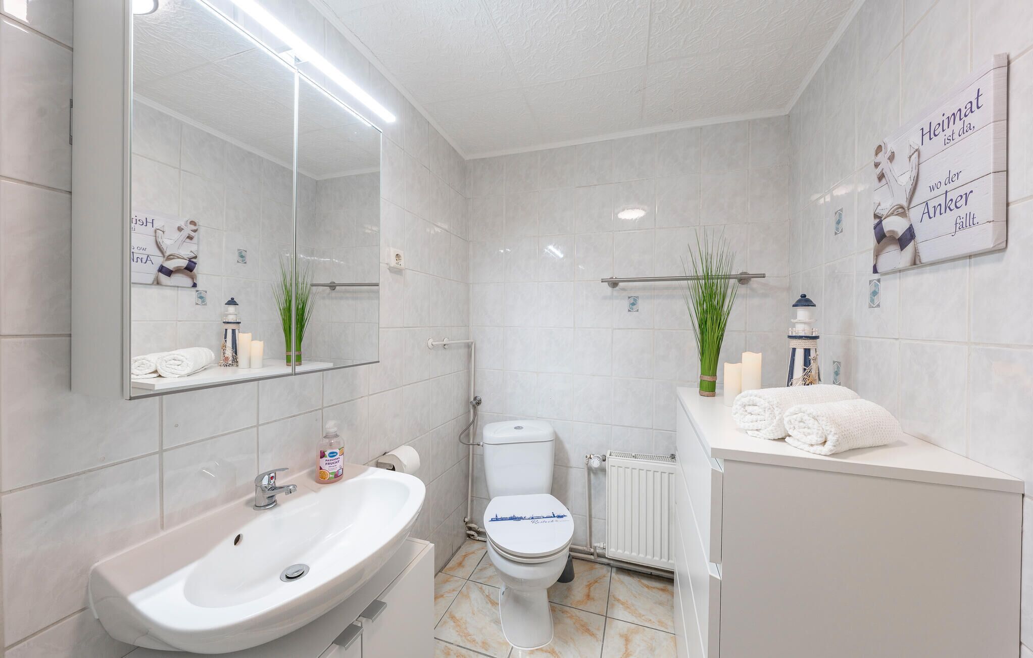 Une salle de bain moderne avec un grand miroir, un lavabo, des toilettes et un porte-serviettes.