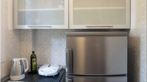 Une cuisine équipée d’appareils électroménagers en acier inoxydable, notamment un réfrigérateur et une bouilloire, ainsi qu’une balance posée sur le plan de travail.