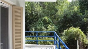 Un balcon doté d’une balustrade bleue, donnant sur un jardin à la végétation luxuriante.