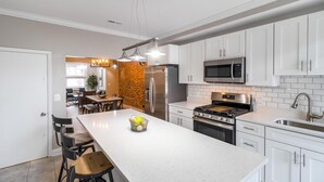 Una cocina moderna con muebles blancos, electrodomésticos de acero inoxidable y una isla central.