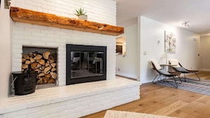 A living room with a white brick fireplace, a black wood-burning stove, and two leather chairs.