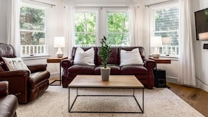 A living room with a brown leather sofa, a coffee table, and a potted plant.