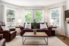 A living room with a brown leather sofa, a coffee table, and a potted plant.