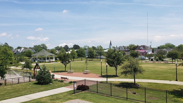 Un parque con un pabellón, mesas de picnic y un parque infantil.