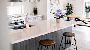 A modern kitchen with a large island, stainless steel appliances, and a marble backsplash. - Luxury Waterfront Grand Villa in Melbourne (Point Cook)