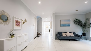 A modern living room with a sofa, a large mirror, and a framed picture on the wall. - Luxury Waterfront Grand Villa in Melbourne (Point Cook)