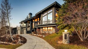 A modern two-story house with a stone foundation, large windows, and a stone pillar with a plaque. - Abode at Bluebird, private hot tub, steps to Main Street & trails (Park City)