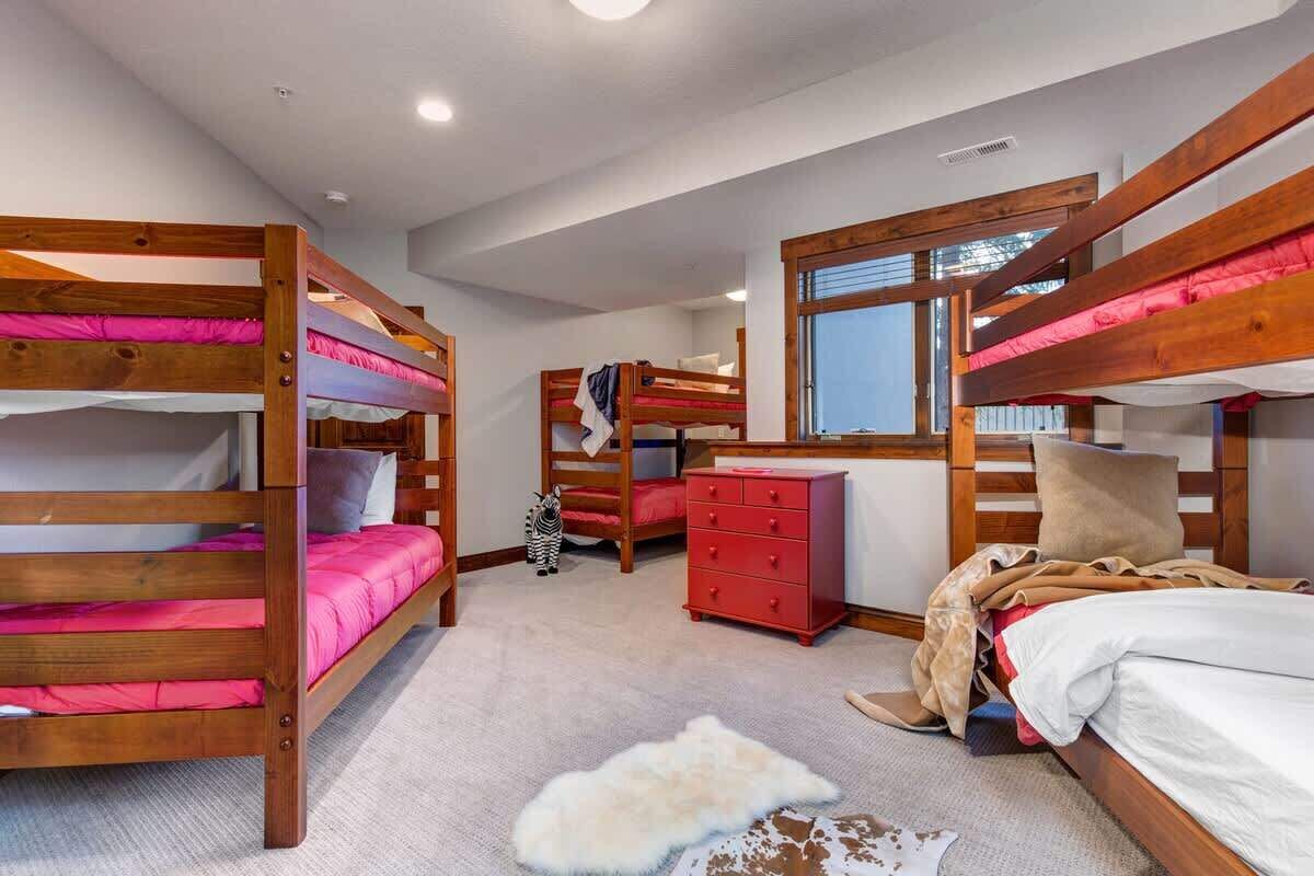 Una habitación con literas, un aparador rojo y una ventana.
