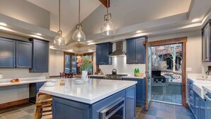 A modern kitchen with dark blue cabinets, a large island, stainless steel appliances, and pendant lighting. - Abode at Bluebird, private hot tub, steps to Main Street & trails (Park City)