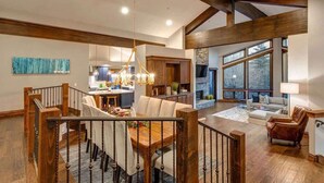 A spacious living area with a dining table, a fireplace, and large windows. - Abode at Bluebird, private hot tub, steps to Main Street & trails (Park City)