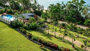 Um resort com piscina, vegetação exuberante e vista para o mar.