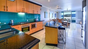 Cozinha moderna com armários de madeira, bancada preta e vista para uma varanda.