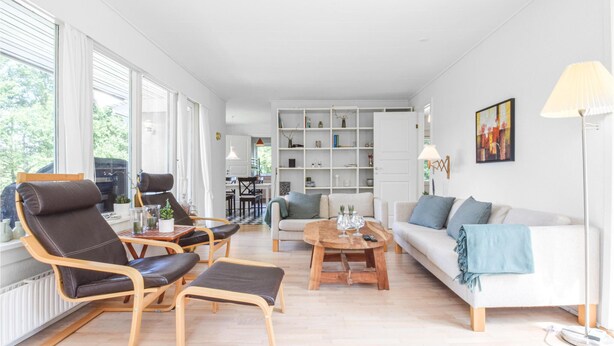 En moderne stue med sofa, stole, sofabord og reol.