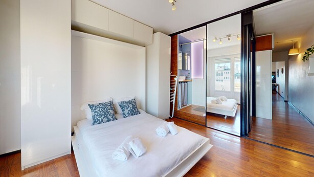 Un dormitorio moderno con una cama grande, un vestidor y un baño al que se accede por un gran ventanal corredera.