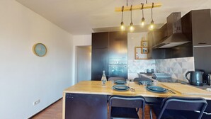 Una cocina moderna con una isla central, horno integrado y una lámpara colgante.