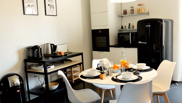 Una cocina moderna con una mesa de comedor, sillas y diversos electrodomésticos.