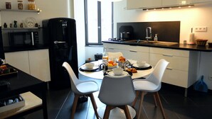 Una cocina moderna con una mesa de comedor, sillas, una cafetera y un ventanal.