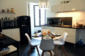 A modern kitchen with a dining table, chairs, a coffee machine, and a window. - chez thomas 72m2 colmar 2br (Colmar)