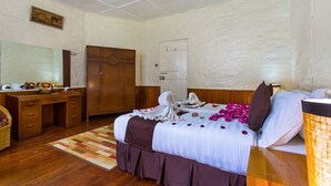 A hotel room with a wooden desk, a bed with a white and brown bedspread, a wooden wardrobe, and a large mirror on the wall. - Thomson Falls Lodge (Nyahururu)