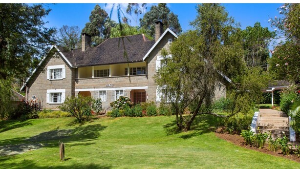 A two-story stone house with a well-maintained lawn and garden. - Thomson Falls Lodge (Nyahururu)