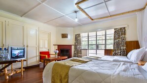 A hotel room with a large bed, a television, a fireplace, and a window with curtains. - Thomson Falls Lodge (Nyahururu)