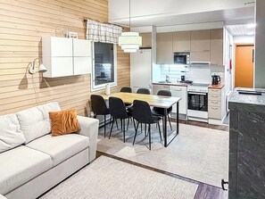 A compact living space with a sofa, dining table, chairs, a kitchenette, and a small kitchen area.