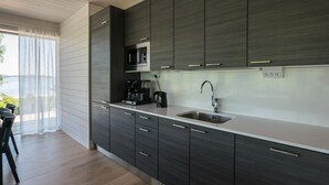 Una cocina moderna con armarios oscuros, un lavamanos de acero inoxidable y una cafetera.
