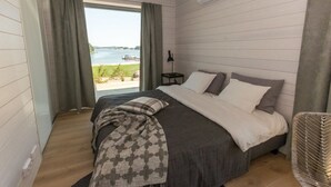 Un dormitorio con una cama grande, vistas al exterior y una ventana con cortinas.