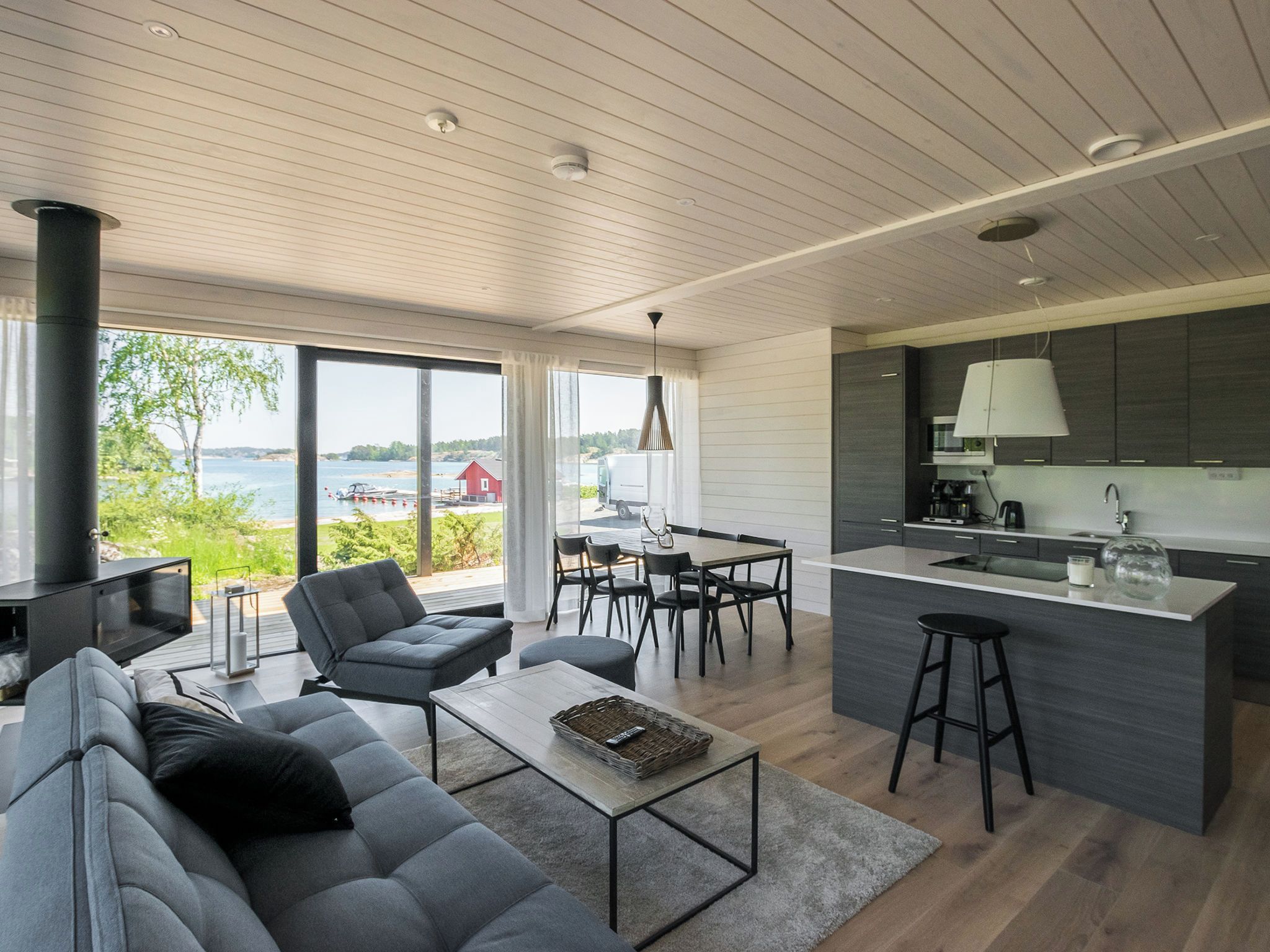 Ett modernt vardagsrum med soffa, soffbord, matplats och kök.