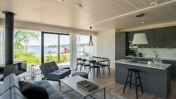 Ett modernt vardagsrum med soffa, soffbord, matplats och kök.