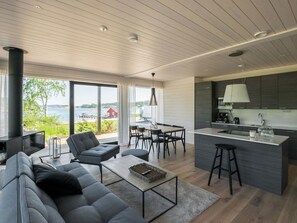 Ett modernt vardagsrum med soffa, soffbord, matplats och kök.