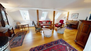 A spacious loft with high ceilings, a wooden floor, a checkered sofa, a piano, and a dining area with a table and chairs. - emilie 145m2 ac 1 free parking 4br 2bth (Strasbourg)