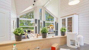 Eine Küche mit einem großen Fenster, einer Spüle, einer Kaffeemaschine und einem Schrank mit Glastüren.