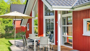 Ein rotes Gebäude mit einer Terrasse, Außenbestuhlung und einer Pergola.