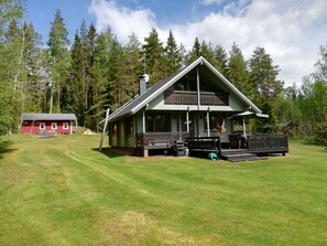 A two-story cabin with a balcony, surrounded by a well-maintained lawn and dense forest. - Kotimäki by Interhome (Hämeenlinna)