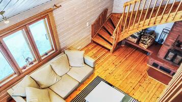 L'intérieur d'une cabane avec un escalier en bois, un canapé et une cheminée.