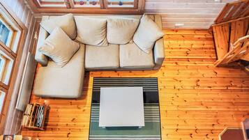 Une pièce chaleureuse avec un canapé d’angle, une grande fenêtre et des murs en bois.
