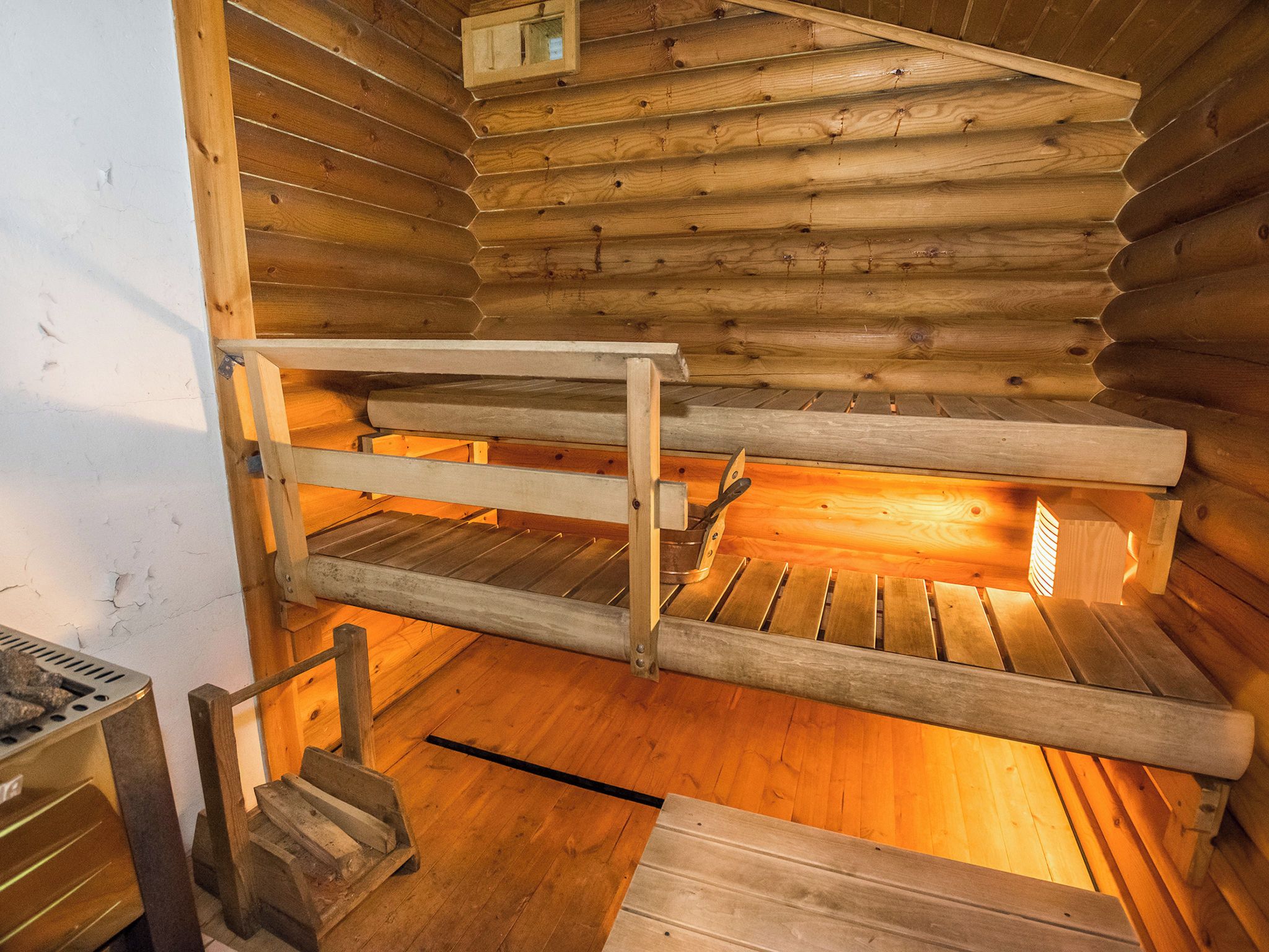 Et interiør af en hytte med køjesenge og pejs.