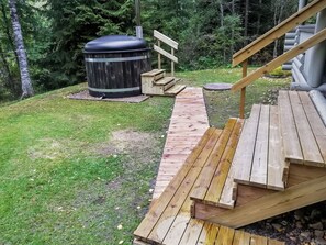 Une terrasse en bois menant à un jacuzzi et un escalier en bois.