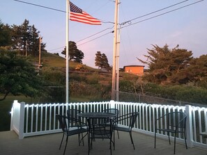 Eine Terrasse mit Tisch und Stühlen, eine amerikanische Flagge und ein weißer Zaun.